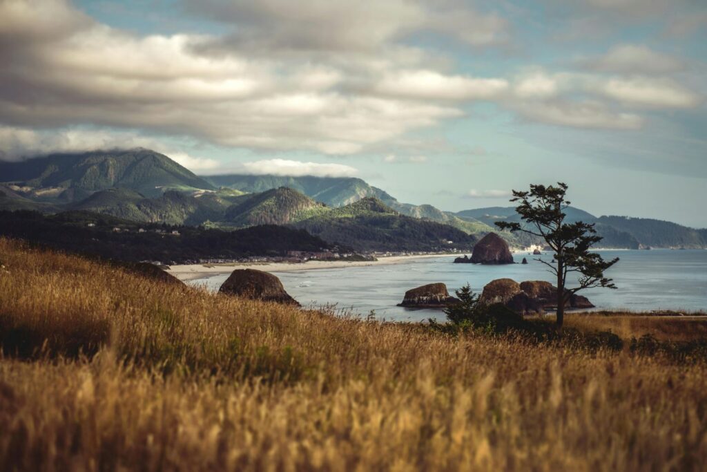 Scenic view of Cannon Beach, Oregon with sea stacks and coastal mountains — a moody and majestic stop on the best beach vacations USA summer 2025.