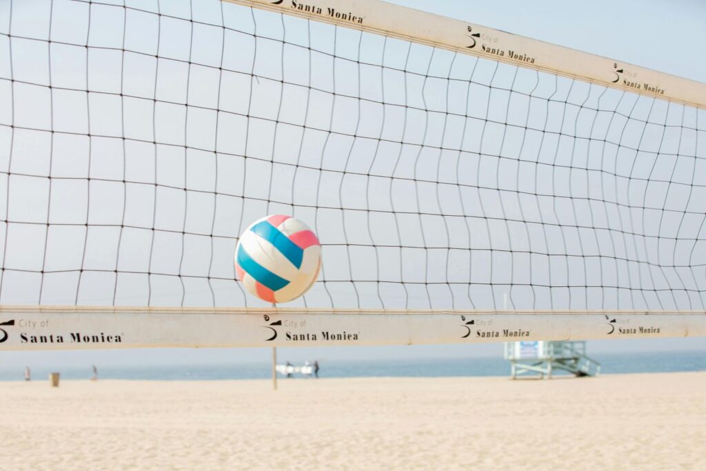Beach volleyball net with a colorful ball midair on Santa Monica Beach, California — an iconic scene from one of the best beach vacations USA summer 2025.