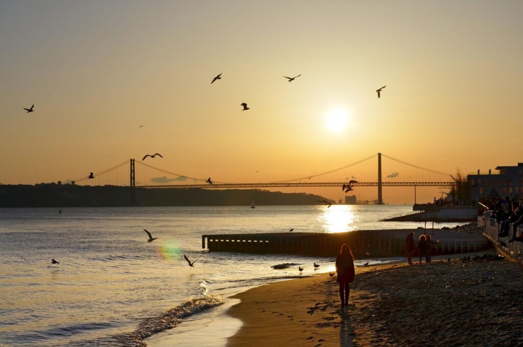 Sunset over the Tagus River with Lisbon’s 25 de Abril Bridge and seagulls in flight — a classic view in this Lisbon travel guide.
