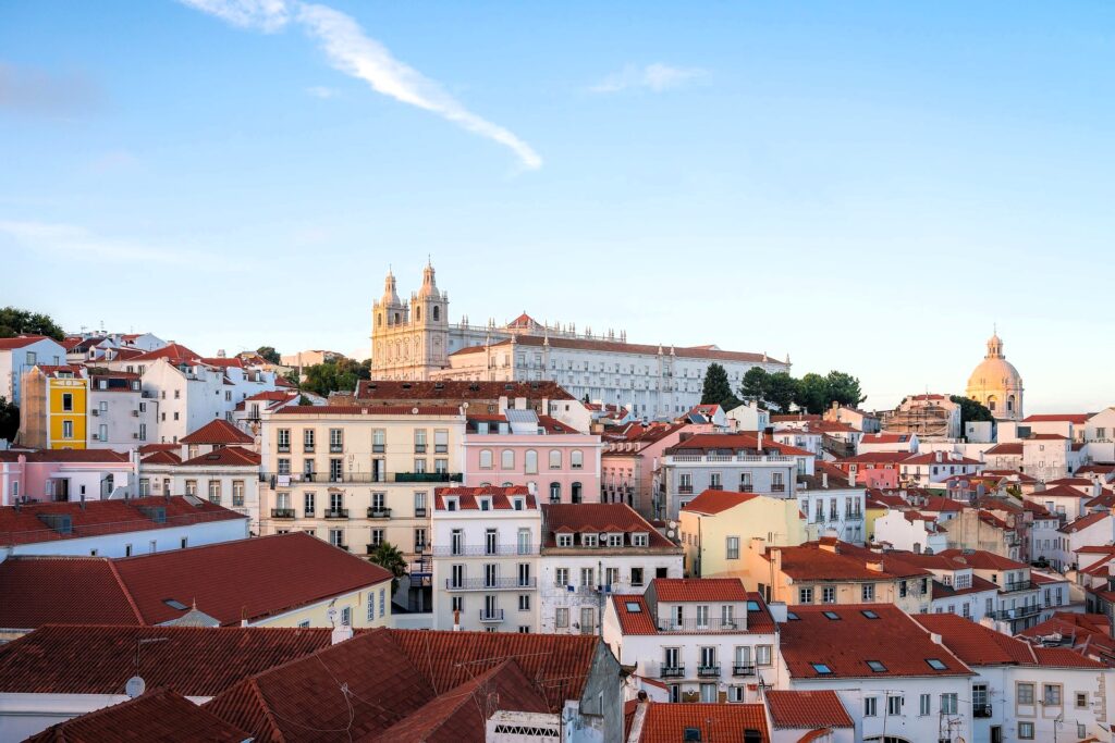 View of Lisbon’s historic Alfama district with red rooftops, pastel buildings, and the National Pantheon in the background — a highlight of this Lisbon travel guide.
