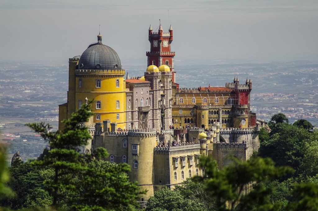Pena Palace in Sintra, Portugal, with vibrant red and yellow towers rising above the treetops — a standout landmark in this Lisbon travel guide.