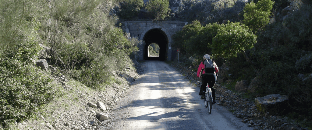 Cyclist riding through a mountain tunnel along the Vía Verde de la Sierra cycling trail in Andalusia, Spain