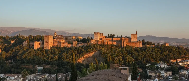 Panoramic view of the Alhambra Palace fortress complex in Granada Spain at sunset from the Mirador de San Nicolas viewpoint.