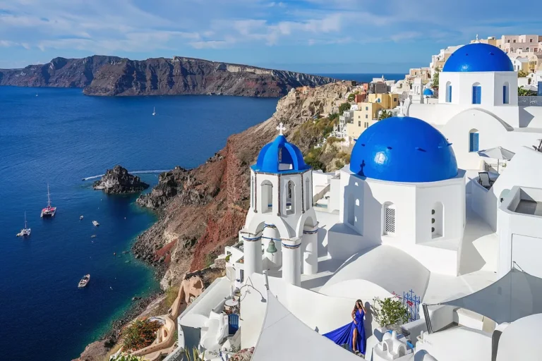The famous three blue domed churches of Oia overlooking the deep blue volcanic caldera sea in Santorini, Greece.